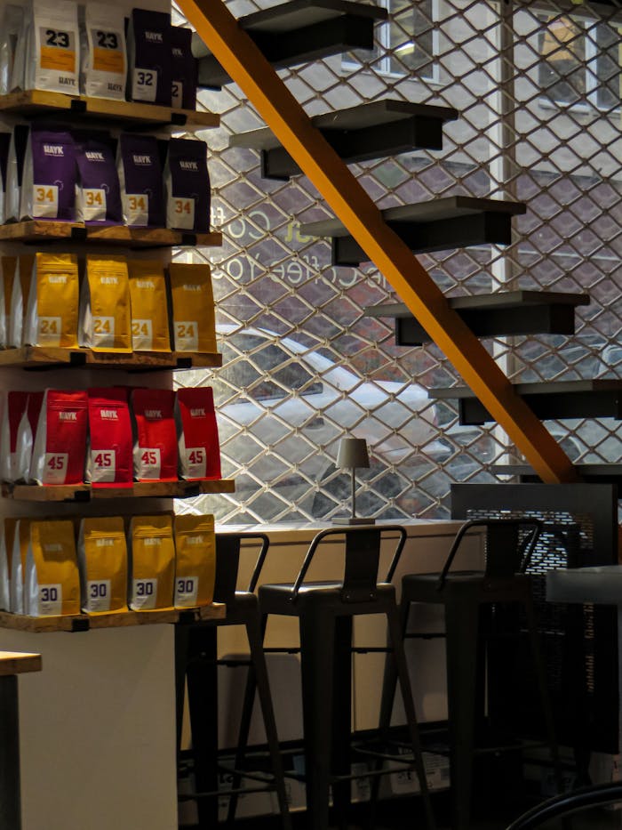 services-03 Cozy modern coffee shop interior featuring packaged coffee and sleek black stools.