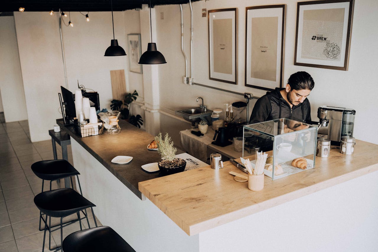 why-choose-us A barista works in a modern café with minimalistic décor and warm lighting.